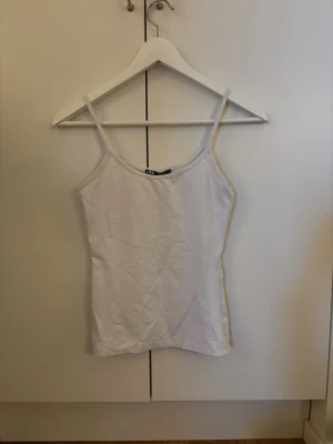 Vit linnetopp från Zara - En enkel och stilren vit linnetopp från Zara med smala axelband och rak passform.