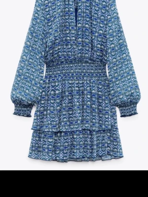 Blå mönstrad kortklänning med volang - Supersöt populär blå kortklänning med långärmade ärmar och volangdetaljer. Klänningen är från Zara i storlek S!🥰