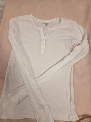 Vit topp med knappar - En supergullig vit topp med knappar längst upp från Brandy Melville! Den är one size, men jag skulle säga att den sitter som M. Den är helt oanvänd då jag köpte men den tyvärr aldrig använde. Den har inga defekter! Nypris är 230 kr, och mitt pris går att diskutera!🤗