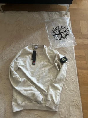 🔥 Stone Island Grå Sweatshirt – Helt Ny med Tags! 🔥 - Säljer en helt ny grå Stone Island sweatshirt – aldrig använd! Kommer med originalpåse och prislapp kvar, så du vet att den är 100% äkta och i perfekt skick.  ✨ Detaljer: • Storlek: S (passar även XS för en lite mer oversized fit) • Skick: Helt ny • Färg: Stilren grå – lätt att matcha 🔥 • Medföljande: Originalpåse + prislapp  💬 Pris: Kan diskuteras vid snabb affär 📦 Frakt: Skickas samma dag vid snabb betalning  Perfekt för en clean streetwear look – först till kvarn!