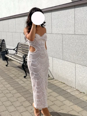 Vit långklänning med pärldetaljer - Supersnygg vit långklänning med pärlbroderier och cut-outs i midjan. Klänningen har smala axelband och en figurnära passform som framhäver siluetten. Perfekt för speciella tillfällen där du vill sticka ut. Passar XS-S 