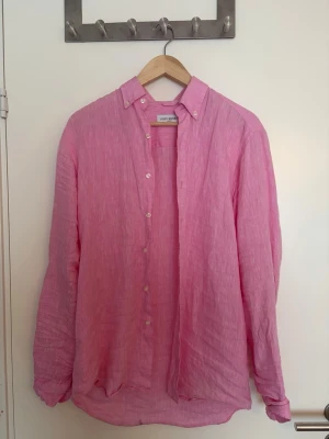  linneskjorta John Henric  - Snygg rosa skjorta från Zara Man i luftigt linne. Skjortan har klassisk krage, knäppning framtill och långa ärmar. Perfekt för en avslappnad och trendig stil.