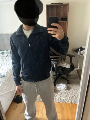 Mörkblå vindjacka från Peak Performance - Snygg mörkblå vindjacka från Peak Performance med dragkedja framtill och hög krage. Jackan har diskret logga på ärmen och en clean, minimalistisk look. Perfekt för dig som gillar stilrena plagg med sportig känsla.