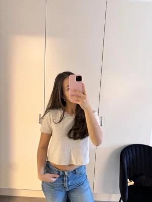 Ljusbeige croppad topp - Säljer en enkel och stilren ljusbeige croppad topp med korta ärmar. Toppen har en rund halsringning och är tillverkad i ett mjukt material som känns skönt mot huden. Perfekt att matcha med jeans eller kjol för en avslappnad look.