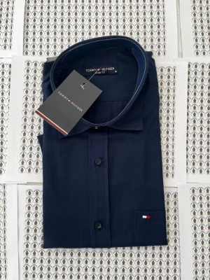 Mörkblå skjorta Tommy Hilfiger - Snygg mörkblå skjorta från Tommy Hilfiger i slim fit-modell. Skjortan har klassisk krage, knäppning framtill och en liten broderad logga på bröstet. Tillverkad i mjukt bomullstyg för en clean och stilren look.