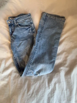 Ljusblå bootcut jeans med slitningar - Säljer mina ljusblå lågmidjade bootcut jeans från Gina tricot. Storleken är 170. Jeansen har hål på båda knäna och även lite snygga slitningar. Köpte dessa förra året och andvänt de 1 gång de är långa och passar perfekt💘