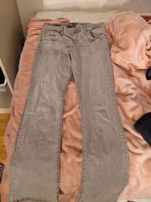 Grå bootcut jeans från LTB - Säljer ett par snygga grå bootcut jeans från LTB. Jeansen har klassisk femficksdesign, låg midja och är tillverkade i mjukt denimtyg. Perfekta för dig som gillar en avslappnad men trendig look. Minimalt slitage vid botten av byxbenen, inget man tänker på.
