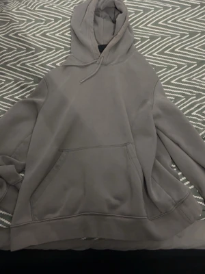 Grå oversized hoodie med ficka - Säljer en stilren grå hoodie med huva och stor magficka. Hoodien har en avslappnad passform och dragsko i huvan. Perfekt för en chill och casual look. Materialet känns mjukt och bekvämt mot huden.