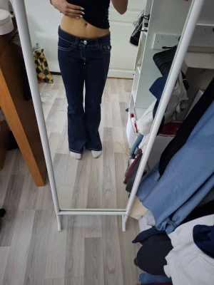 Mörkblå bootcut jeans med kontrastsömmar - Säljer ett par mörkblå bootcut jeans från Gina Tricot. Jeansen har vita kontrastsömmar och klassiska fem fickor. Använda endast en gång. Ny pris 400kr.