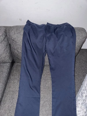 Mörkblå kostymbyxor från Puma - ”Golfbyxor” Snygga mörkblå kostymbyxor från Puma med raka ben och klassisk passform. Byxorna har två fickor bak och diskret Puma-logga ovanför ena bakfickan. Perfekta för en stilren look och passar till skjorta eller t-shirt. Använda 1 gång