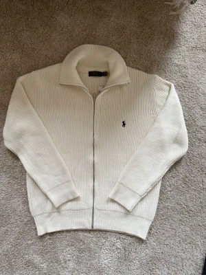 Ralph lauren cardigan - Riktigt snygg krämfärgad ralph lauren cardigan, den är i utmärkt skick utan defekter och är i storlek XL, modellen är 183cm lång