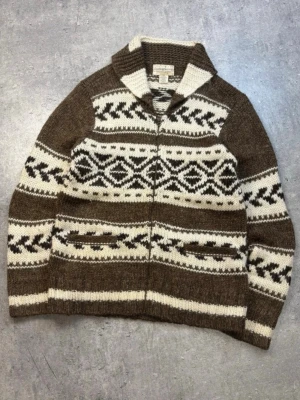 Brunvit kofta med mönster från Cowichan Ralph lauren denim and supply size L - Säljer en chunky stickad kofta i brunt och vitt med klassiskt cowichan mönster och dragkedja framtill. Koftan har bred krage och två fickor. Materialet är en blanding av ull, akryl, linne och alpacka den har en retro känsla med snygga detaljer. Perfekt för dig som gillar vintage och stickat. Materialblandingen gör ett den får ett hårigt uttryck likt mohairull. Står size m på tagg men sitter som en L. Jag är 184 och väger 75kg på sista bilden. 