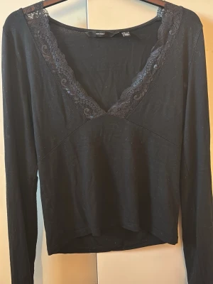Svart långärmad topp med spets Vero Moda - Svart långärmad topp från Vero Moda med djup v-ringning dekorerad med spetsdetaljer. Tunn och mjuk i materialet,bra skick💕💕
