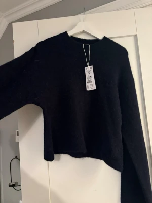 Mörkblå stickad tröja  - Säljer en mörkblå stickad tröja från Gina Tricot med lös passform och rund hals. Tröjan har långa ärmar och är gjord i ett mjukt, fluffigt material som känns riktigt mysigt. Perfekt för dig som gillar en enkel men trendig look. Helt ny! 