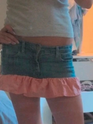 Jeanskjol med rosa volang - Säljer en jeans kjol med en söt rosa volang längst ner. Kjolen har låg midja, klassiska fickor och bälteshällor. Perfekta för sommarens alla äventyr! Märket är sunshine