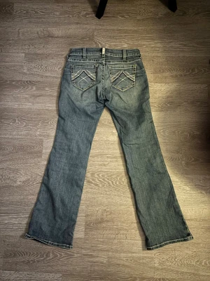 Bootcut jeans  - Mörkblå/gråaktiga bootcut jeans från Ariat real denim i storlek waist 29. Riktigt snygga detaljer på fickorna säljer då dom inte passade.               Nypris: 1199 kr 