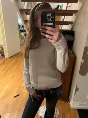 Vit stickad tröja med rund hals - Jättegullig och en enkel och stilren vit stickad tröja med rund halsringning och långa ärmar. Tröjan har ribbstickade muddar vid ärmslut och nederkant. Perfekt att matcha med jeans för en avslappnad look.