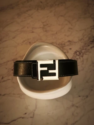 Svart Fendi bälte med silverdetalj - Tvär fett Fendi bälte, passar i alla möjliga outfits och gör hela outfiten mycket fetare. Trots sån simpel design så ser den fortfarande dyr och exklusiv ut 