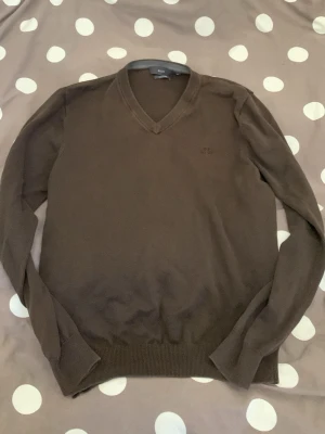 Brun V-ringad stickad tröja Riley! - Mjuk och stilren brun stickad tröja från Riley i Pima bomull. Tröjan har V-ringning, långa ärmar och ribbade muddar vid ärmslut och nederkant. Perfekt för dig som gillar klassisk och enkel stil. Lite liten för mig!