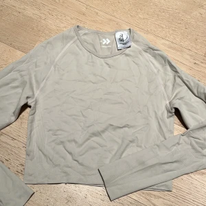 Beige långärmad topp från lager 157  - Säljer en beige långärmad topp från lager 157 . Modellen är croppad med rund halsringning och har en stilren, enkel design utan synliga mönster eller detaljer. Perfekt för dig som gillar sportig och minimalistisk stil.