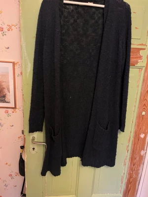 Mörkblå lång kofta med fickor - Mysig mörkblå lång kofta i stickat material med två framfickor och öppen front. Storlek M men observera att den är lång på längden. Priset kan alltid diskuteras, hör av er om fler bilder.