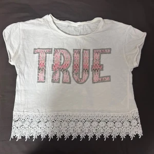 Vit croppad topp med spetskant - Vit croppad topp med trycket 'TRUE' i rosa och grått med blommigt mönster