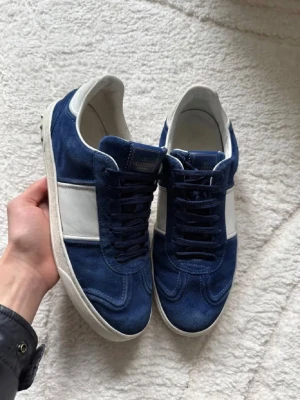 Valentino flycrews ÄKTA - Snygga sneakers från Valentino i blå mocka med vita detaljer och vit sula. Klassisk låg modell med svarta skosnören och logotyp på plösen. Perfekta för dig som vill ha en stilren och exklusiv look. Köptes för 8999kr