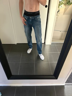 Blå raka jeans från Jack&jones - Snygga blå jeans från Jack&jones med rak passform och klassisk femficksdesign. Jeansen har normal midja och subtila slitningar för en avslappnad look. Perfekta till vardags och passar till det mesta i garderoben.
