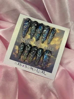 CyB3R (S);Long Stiletto - Unika press-on naglar i svart med blå och silvriga inslag, dekorerade med silverfärgade linjer och små stenar. Naglarna har en spetsig, lång form och en cool, mystisk vibe. Perfekta för dig som vill sticka ut med en edgy look.