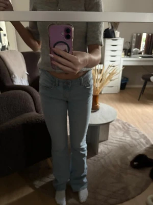 Ljusblå bootcut jeans - Säljer ett par ljusblå bootcut jeans med klassisk femficksdesign och normal midja. Jeansen har en snygg tvätt och raka ben som går ut lite nedtill. Perfekta till en avslappnad look och passar till det mesta. Materialet är mjukt denim i bomull.