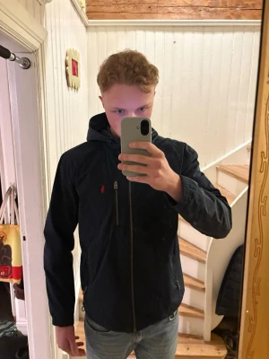 Mörk blå vindjacka från Ralph Lauren - Säljer en Polo Ralph Lauren jacka Storlek Large i fint skick utan anmärkningar. Jackan är mörkblå och går att dra åt nere och i luvan. 