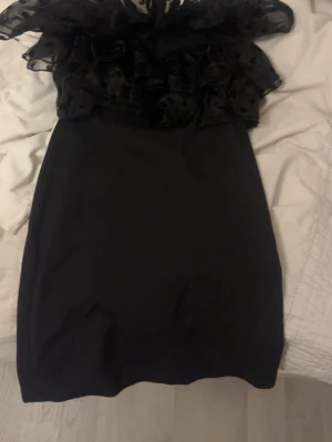 Svart tajt kort klänning med volang upptill - Skitsnygg svart tajt kort klänning med volang upptill från Zara!