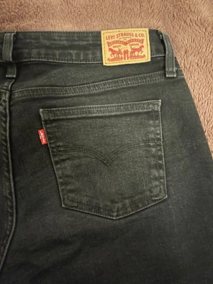 Svarta Levi's jeans med rak passform - Snygga svarta jeans från Levi's med klassisk femficksmodell och rak passform. Jeansen har den ikoniska röda Levi's-lappen på bakfickan och patch i läder bak i midjan. Tillverkade i mjuk och slitstark denim, perfekta till vardagslooken.