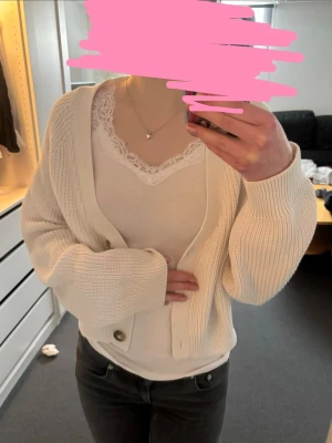 Vit ribbad kofta med knappar - Passar även xs. Säljer en stilren vit kofta med ribbad struktur och stora bruna knappar framtill. Koftan har en avslappnad passform, långa ärmar och är perfekt att slänga över ett linne eller t-shirt. Passar till både jeans och kjol för en enkel look.