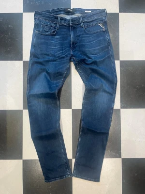 Replay Anbass W33 L34 - W33 L34Snygga blå slim fit jeans från Replay med klassisk femficksdesign och dragkedjedetalj på ena fickan fram. Jeansen har en lätt tvättad look och kontrastsömmar. Tillverkade i mjuk denim som ger en skön passform och modern stil. 