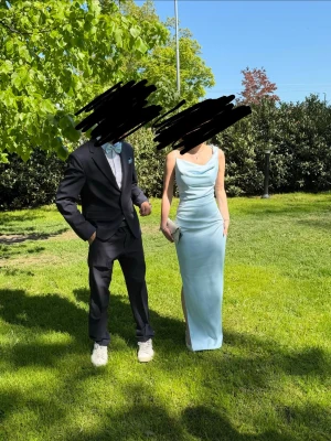 Ljusblå lång klänning med slits - Säljer en elegant ljusblå långklänning med slits på sidan. Klänningen har en figurnära passform och mjukt, glansigt tyg som ger en lyxig känsla. Perfekt för dig som vill sticka ut med en stilren look. Bara använd en gång på balen. Nypris 1600 kr