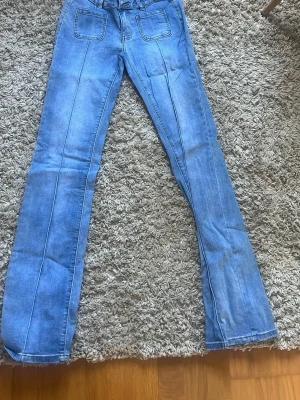 Ljusblå bootcut jeans med fickor - Säljer ett par ljusblå bootcut jeans från Madlady i storlek xtall 36  med markerade sömmar och stora framfickor. Jeansen har även bakfickor med lock och knapp. Klassisk femficksmodell i mjukt denimtyg, perfekta till en avslappnad look. OBS PRIS KAN DISKUTERAS 