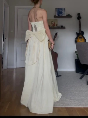 Ljusgul  balklänning - Elegant axelbandslös långklänning i ljusgul ton med stor rosett bak. Säljer denna supervackrq klänningen i nyskick med prislapp på! Skriv vid frågor eller önskan om fler bilder💛
