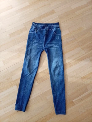 Blå slim fit jeans med slitningar - Snygga blå slim fit jeans med fejkade slitningar och ljusa detaljer framtill. Klassisk femficksmodell med normal midja och smala ben. Jeansen har bälteshällor och är tillverkade i denim med stretch för extra komfort. De ä leggings typ. Storleken står ej men skulle vilja säga den passar S ja ha S