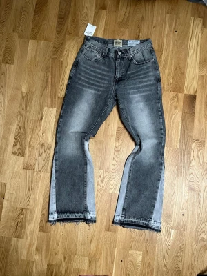 Grå jeans från Gallery Dept. - Säljer ett par grå jeans från Gallery Dept. med snygg tvätt och slitna detaljer vid bensluten. Jeansen har raka ben och klassisk femficksdesign. Perfekta för dig som gillar streetwear och unik stil. Passar som M ska inte ljuga