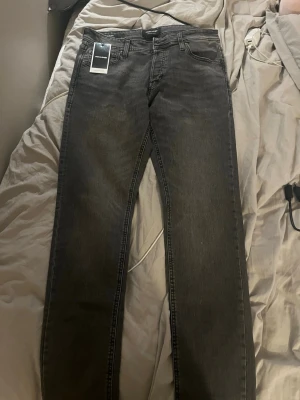 Svarta raka jeans från Jack & Jones - Snygga svarta jeans från Jack & Jones med rak passform och klassisk femficksdesign. Jeansen har en diskret tvättad look och är tillverkade i bomull med lite stretch för extra komfort. Perfekta för en stilren och avslappnad outfit.