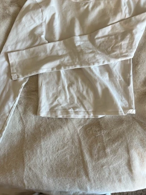 Vit långärmad topp i bomull - En enkel och stilren vit långärmad topp i mjuk bomull. Toppen har en klassisk rund halsringning och rak passform, perfekt att matcha med jeans eller kjol. Skriv för fler bilder eller frågor ❤️