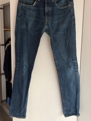 Blå raka vintige jeans från Levi's - Vintige blå jeans från Levi's med rak passform och fem fickor. Jeansen har en snygg tvättad look och är tillverkade i slitstarkt denim. Perfekta för en avslappnad stil och har den ikoniska röda Levi's-lappen bak.