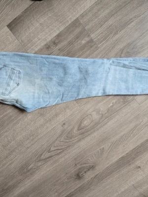 Ljusblå Lynn slimfit jeans från G star Raw 29/32 - Säljer ett par ljusblå jeans med klassisk femficksdesign och slimmade ben. Jeansen har en avslappnad passform och är tillverkade i denim med stretch. Perfekta för en casual look och lätta att matcha med olika stilar. 29/32