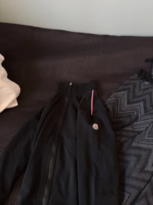 Moncler Cardigan - Säljer nu min svarta Moncler Cardigan då den tyvärr inte passade mig. Är i grymt bra skick och är 100% äkta (bevis finns på sista bilden). Pris är ej hugget i stan. Storlek 4 (XL) men tycker den passar som bäst på M. Fler bilder skickas vid seriöst intresse:)