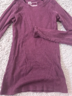 Lila långärmad tröja FSBN Sister XS - Lila långärmad tröja från FSBN Sister i storlek XS. Tröjan är ribbad och har en enkel, tight passform med rund hals. Perfekt att styla med jeans eller kjol för en clean look.