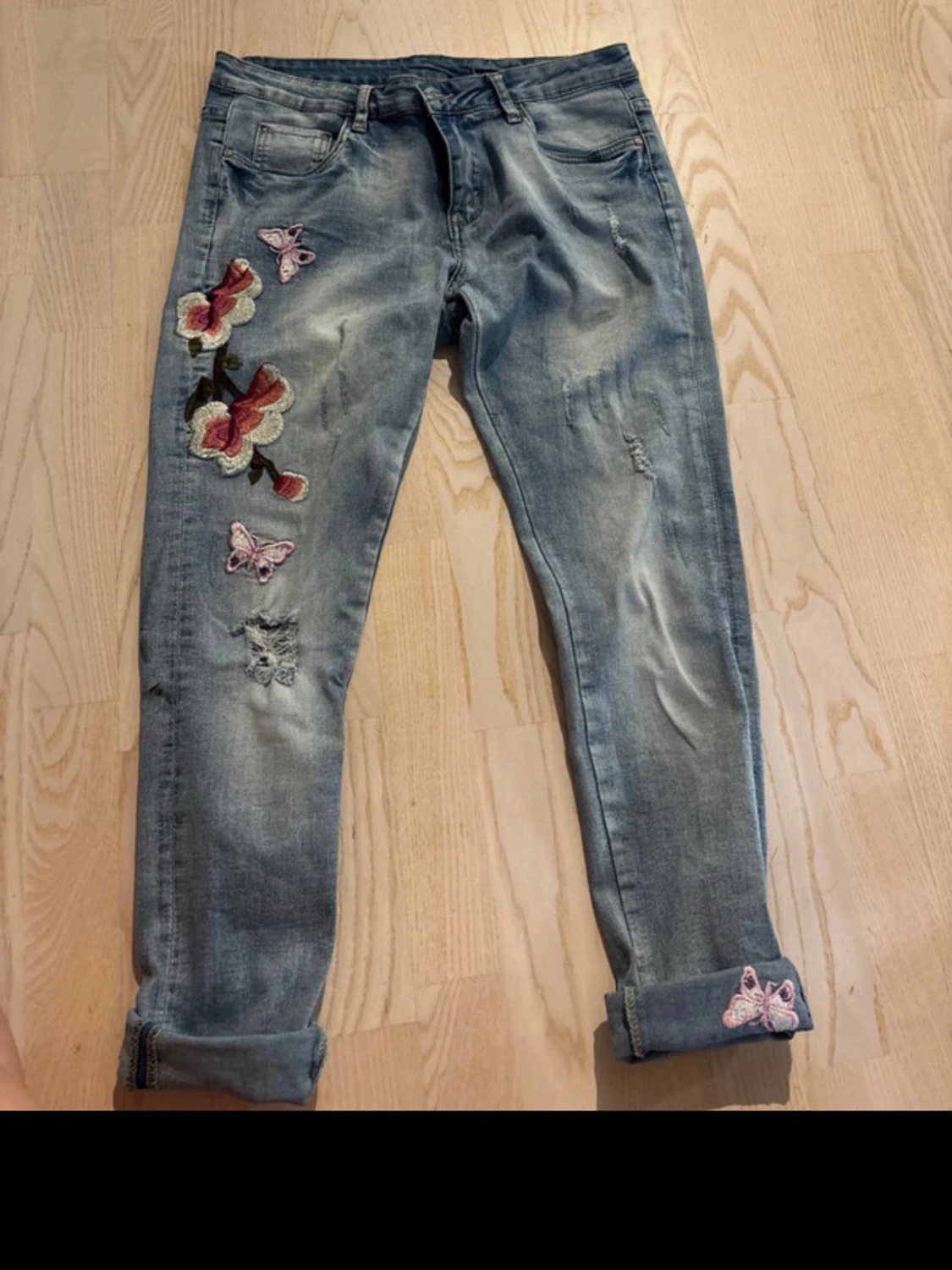 Blå jeans med blommor och fjärilar