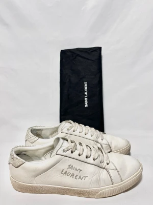 Saint Laurent sneakers vita - Saint Laurent skor i en unik vit modell! Fint skick, inga tydliga defekter. Storlek 40. Dustbag ingår. Kontakta mig för fler frågor och funderingar!