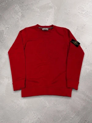 Röd sweatshirt från Stone Island S - Riktigt snygg röd sweatshirt från Stone Island med rund hals och diskret broderad logga framtill. Klassisk patch på vänster ärm. Tillverkad i mjuk bomull som känns skön mot huden. Perfekt till jeans eller cargo för en clean streetwear-look. Pris kan diskuteras vid snabb affär 🔴🔴