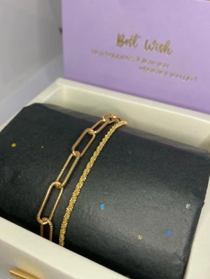 Tvådelat guldarmband set - Snyggt tvådelat armband i guldfärg, ett med större rektangulära länkar och ett smalare med glittrig, texturerad kedja. Perfekt för dig som gillar trendiga accessoarer med stilren design. Passar att bära tillsammans eller var för sig.
